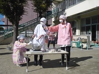 栄養士さんが子どもたちの前で調理実演をしている写真