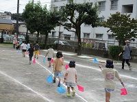 4歳児がフラッグをもって行進している写真です。。