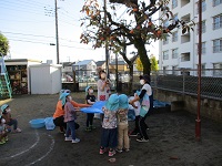 園庭の柿を4歳児クラスが取っている写真です。