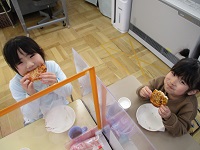 5歳児が自分で作ったピザを食べている写真です。