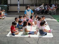 2歳児ぱんだ組の子どもたちが園庭で七夕の職員劇を見ている写真