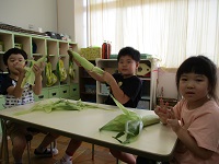 5歳ぞう組の子どもたちがトウモロコシの皮むきをしている写真