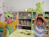 5歳ぞう組の子どもたちがトウモロコシの皮で遊んでいる写真