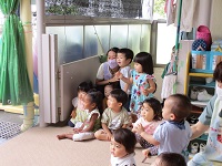 乳児クラスがシャボン玉ショーをみている写真です。