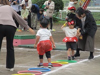 2歳児ぱんだ組の子どもがフープでジャンプをしている写真