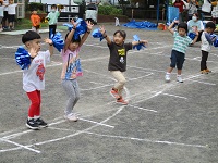 3歳児ポンポンを持って踊っている写真です。