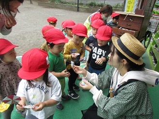 紙芝居屋さんからお菓子のプレゼントをもらう2歳児うさぎ組の子どもの様子の写真