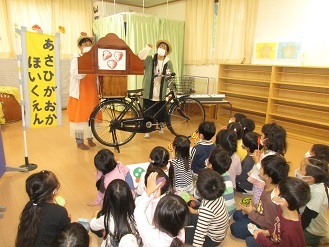 4歳児ぱんだ組が折り紙のペロペロキャンディーを手に持ちながら紙芝居を見ている様子の写真