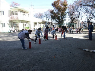 避難訓練で職員が消火訓練を行っている様子の写真