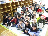 3歳児らいおん組、4歳児きりん組、5歳児ぞう組の子どもたちが集まってこれから誕生会が始まるところの写真