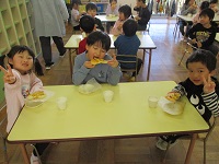 5歳児ぞう組の子どもたちができあがったピザを食べるところの写真