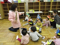 節分の集会で、0歳ひよこ組から2歳ぱんだ組の子どもたちに園長先生が説明をしている写真