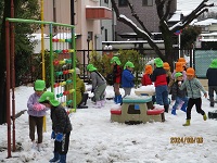 園庭で3歳児らいおん組の子どもたちと4歳児きりん組の子どもたちが、雪遊びをしている写真
