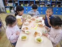 5歳児が豆まき後、給食の節分メニューをを食べている写真です。