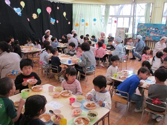 ホールで4,5歳児一緒に会食会をしている様子の写真