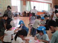 写真：小学生に折り紙を教えてもらっているところ