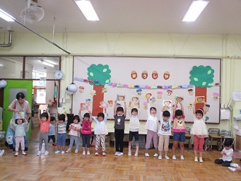 10月生まれの誕生児がカードを上に掲げている様子の写真