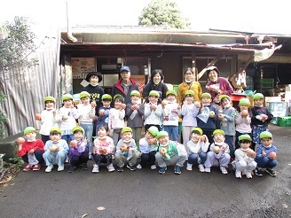 5歳児の子ども達がりんごをもってみんなで集合している様子の写真