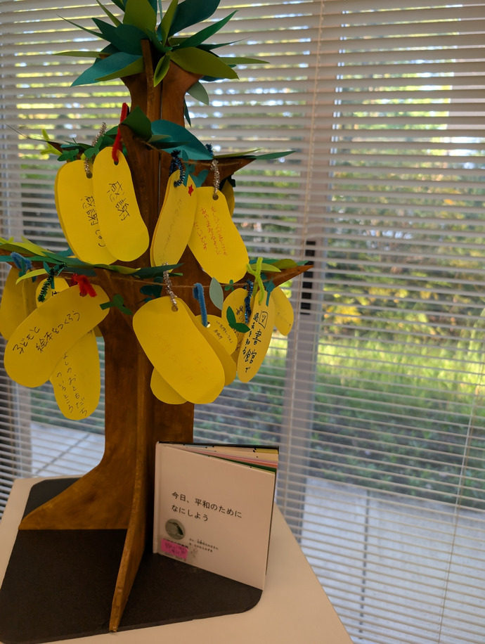 写真：木に展示された「平和のたね」。「感謝」「子どもと絵本をつくろう」など。