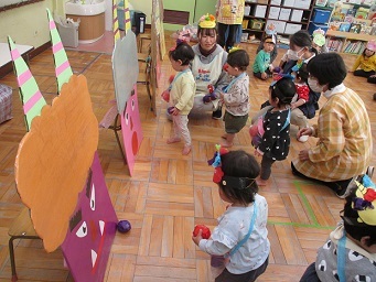 0歳児ひよこ組が鬼ボードに向かって手作り豆を投げている様子。