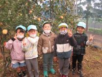 りんごの木の前に立つ子どもたちの写真