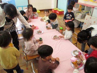 2歳児クラスのおみせやさんで1歳児のクラスのお友達が食べているところ
