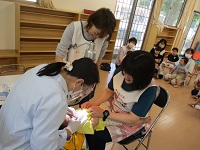 歯科検診を受けている0歳児の様子の写真