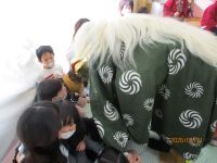 獅子が子供に近づき頭を嚙んでいる写真です。