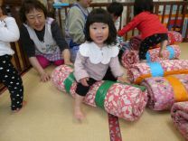 布団棒にまたがって遊ぶ園児の様子の写真