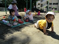 砂場からハイハイで遊んでいる様子の写真