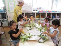 トウモロコシの川をむいている4歳児の様子の写真
