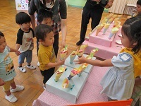 写真：5歳児クラスのクレープ屋さんに2歳児クラスが買いに来ている様子