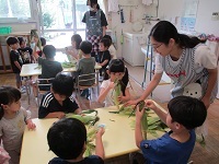 写真：5歳児クラスの子ども達がとうもろこしの皮をむいている様子